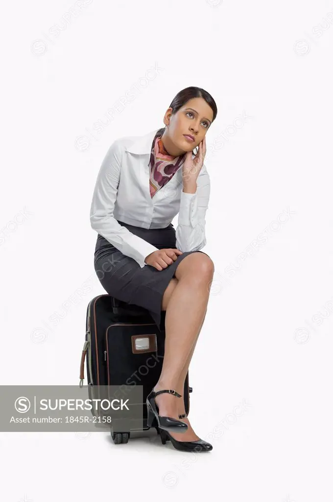 Air hostess sitting on her luggage and thinking