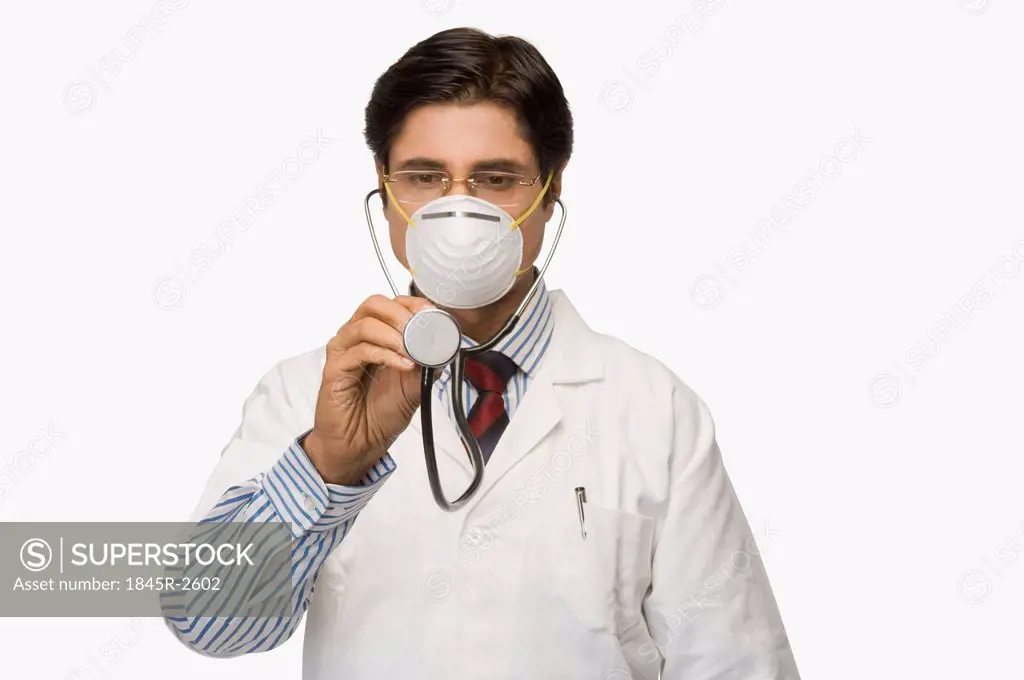 Doctor wearing a flu mask and pretending to listen heartbeat with a stethoscope
