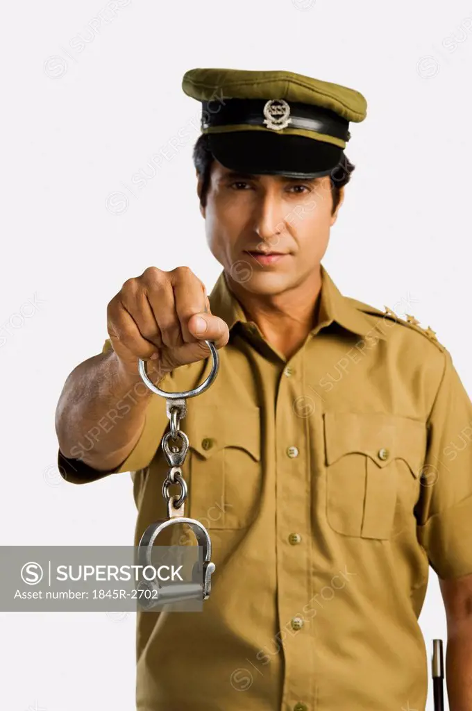 Portrait of a policeman holding a pair of handcuffs