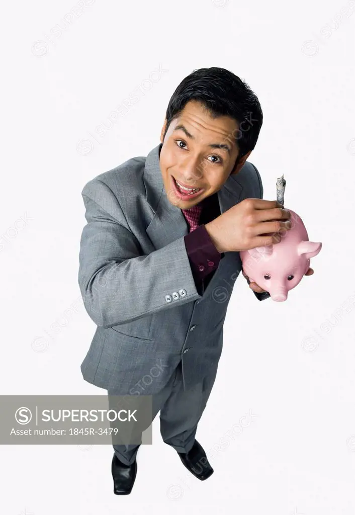 Businessman putting money into a piggy bank