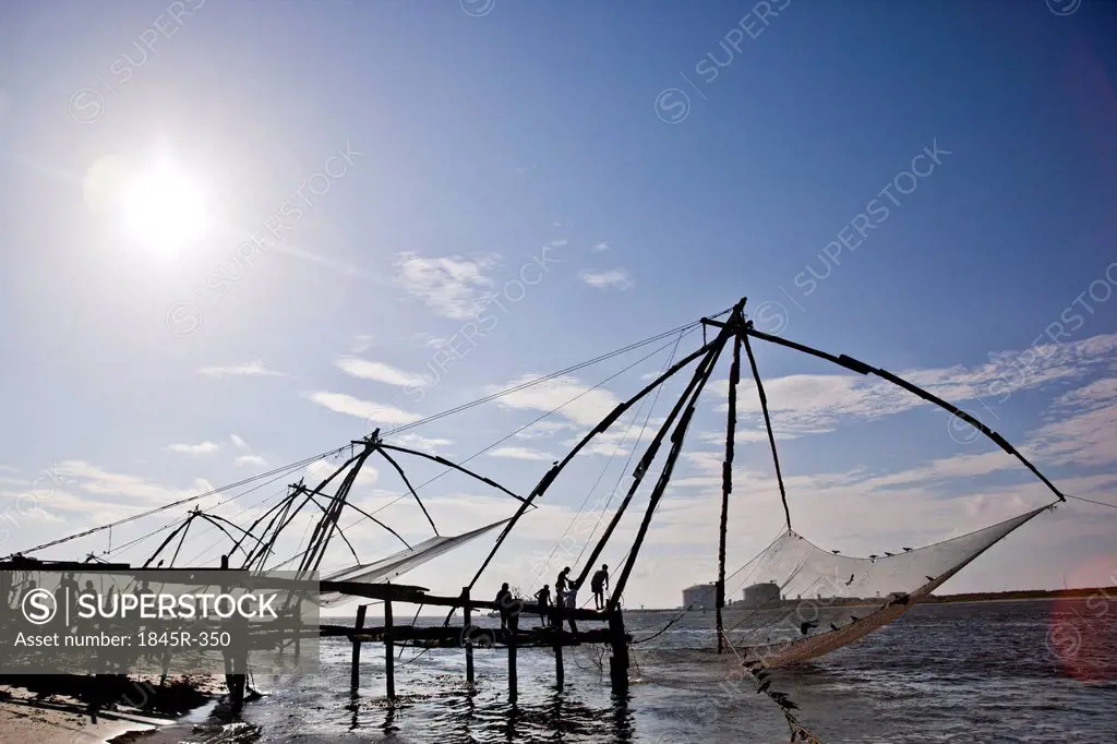 Fishermen with Chinese fishing nets at a harbor, Cochin, Kerala, India