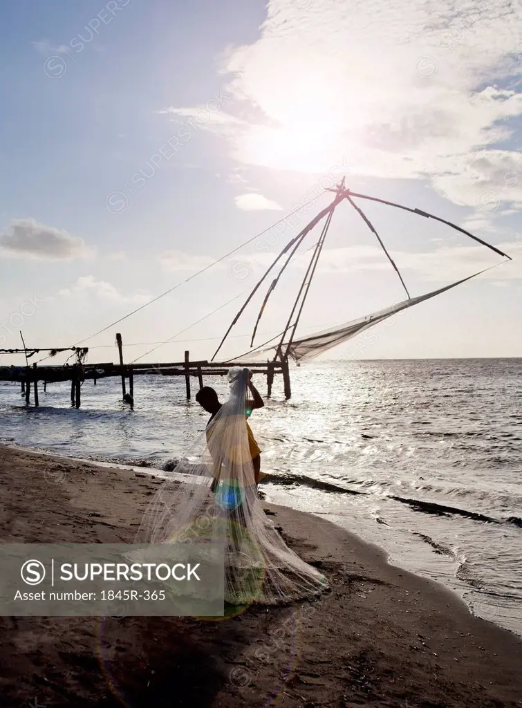 Fisherman holding a fishing net on the beach, Cochin, Kerala, India