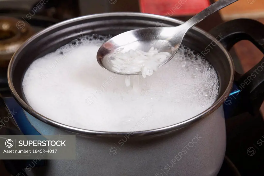 Close-up of a spatula over a pan of rice boiling on a stove