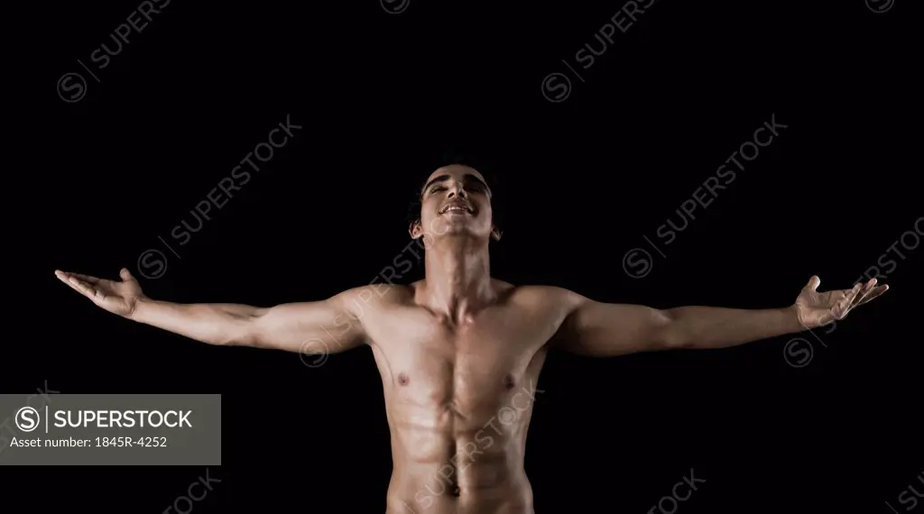 Bare chested man standing with arms outstretched