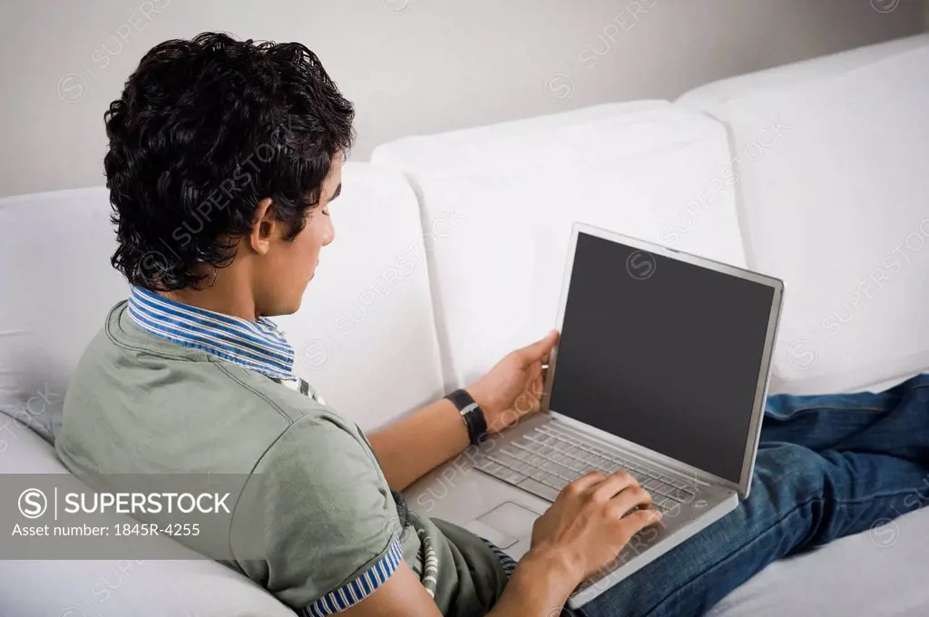 High angle view of a man sitting on a couch working on a laptop