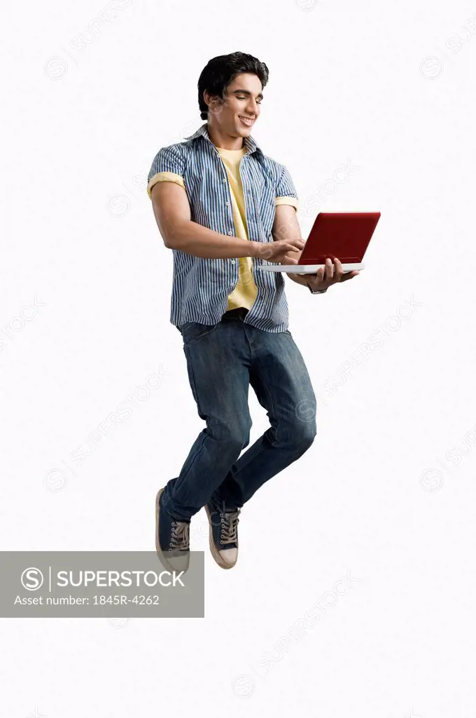 College student using a laptop and jumping