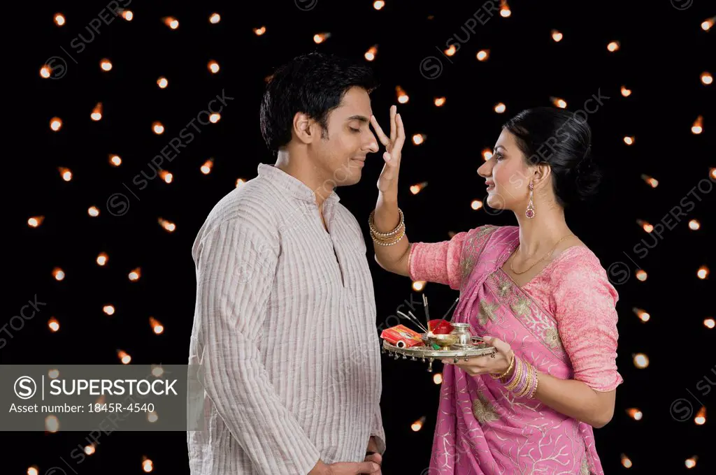 Woman doing tilak of her husband on Diwali