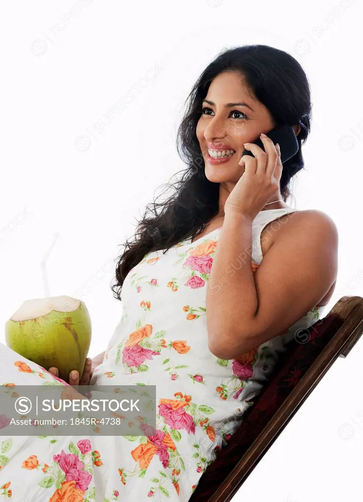 Woman drinking coconut milk and talking on a mobile phone