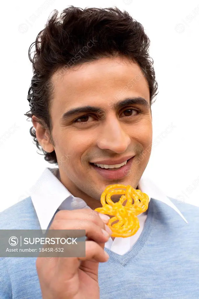 Portrait of a smiling man eating jalebi