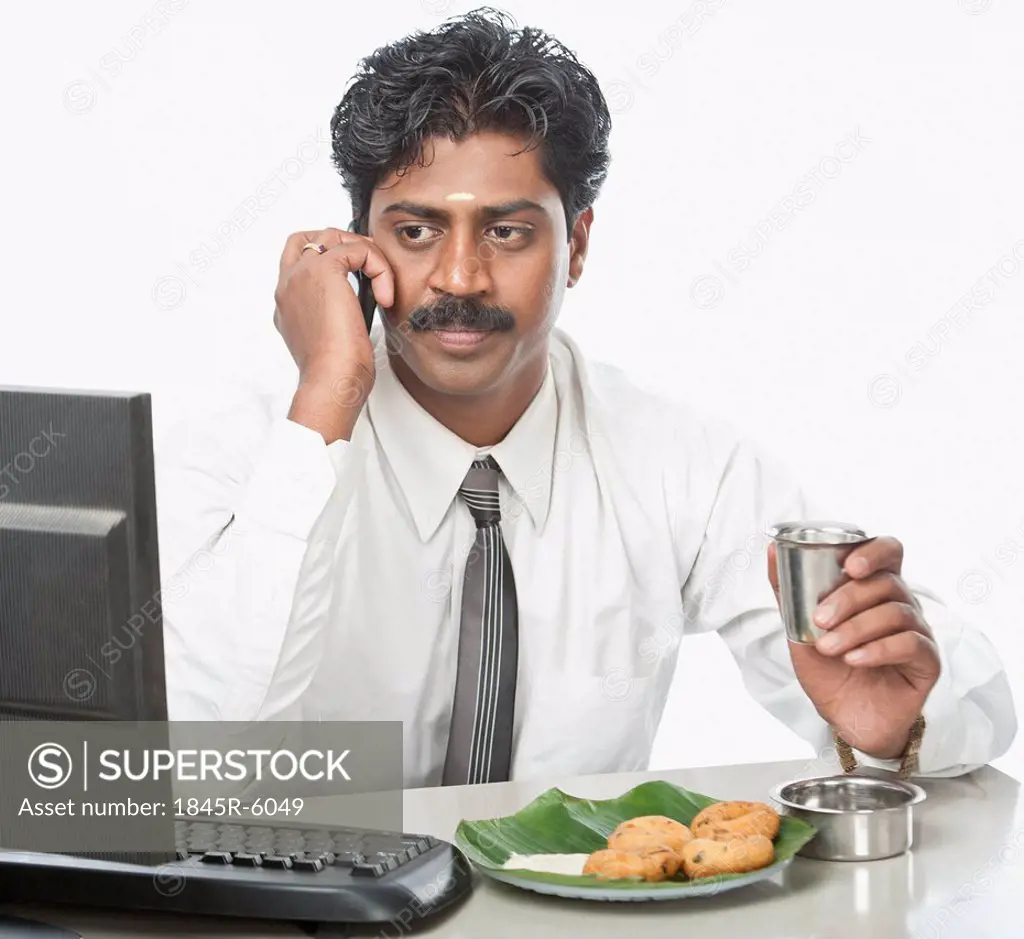 South Indian businessman working in an office and having food