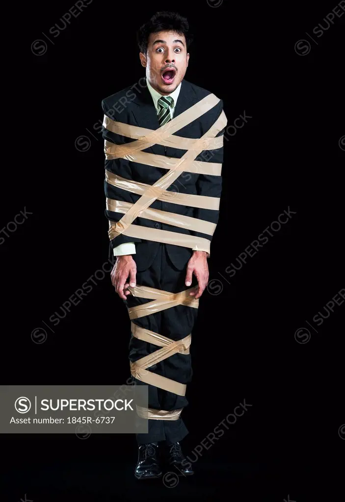 Businessman tied up with adhesive tape looking shocked