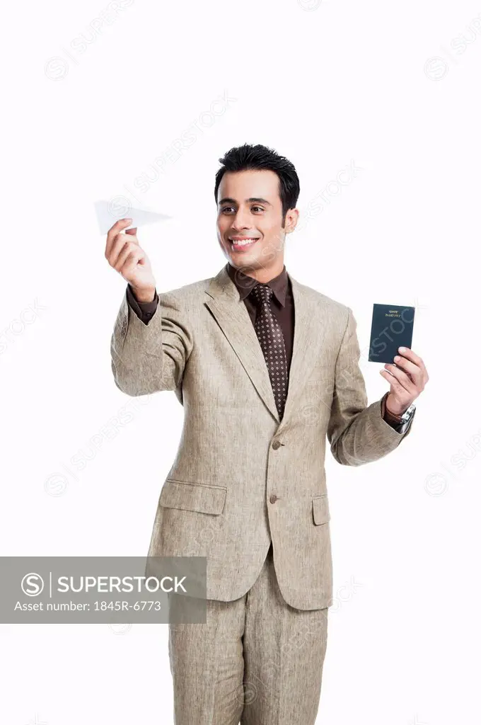 Businessman holding a paper airplane with passport and smiling