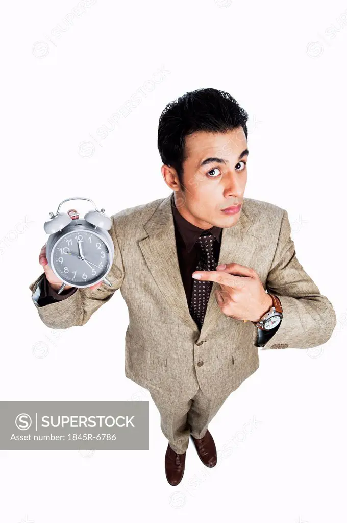 Angry businessman pointing towards an alarm clock