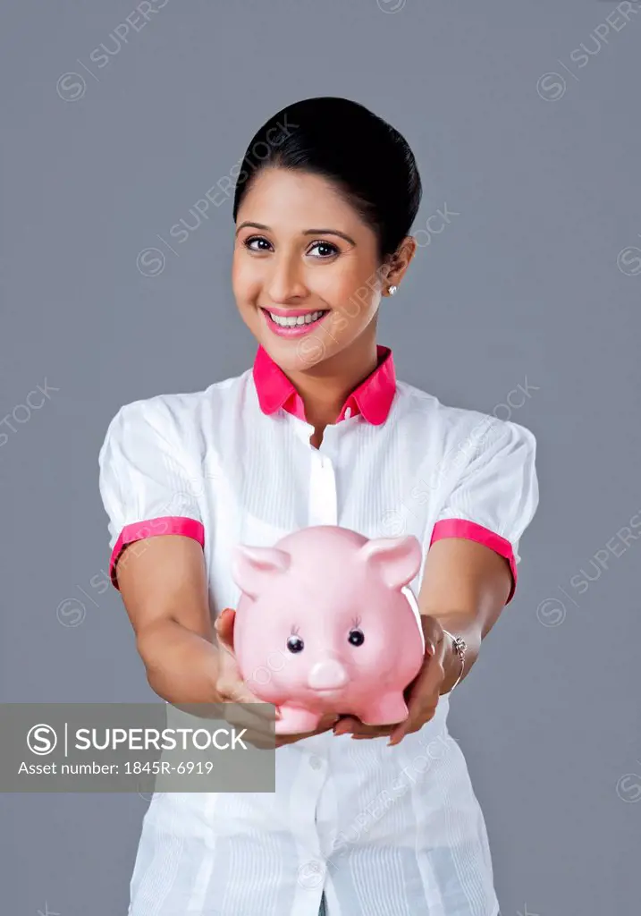 Portrait of a woman holding a piggy bank