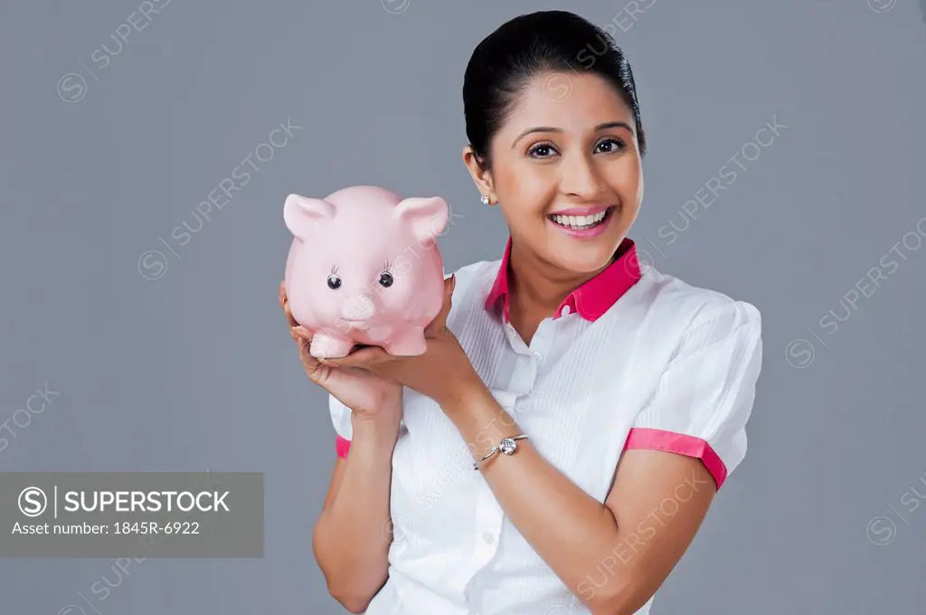 Portrait of a woman holding a piggy bank