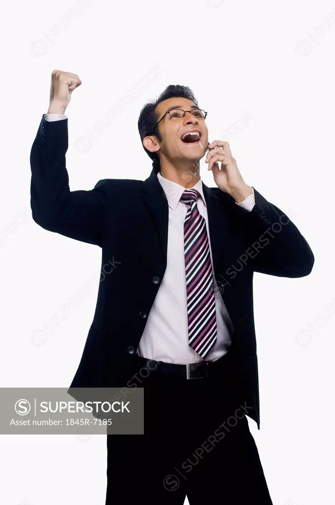 Businessman clenching fist while talking on a mobile phone