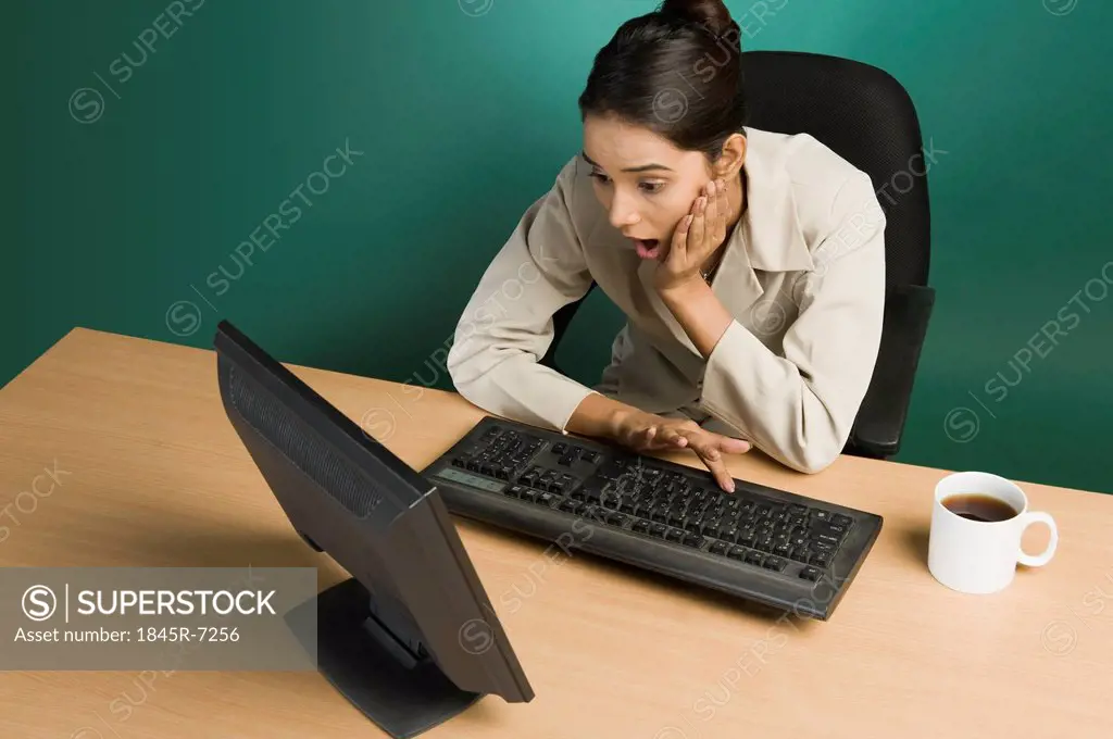 Businesswoman working on a computer and looking surprised