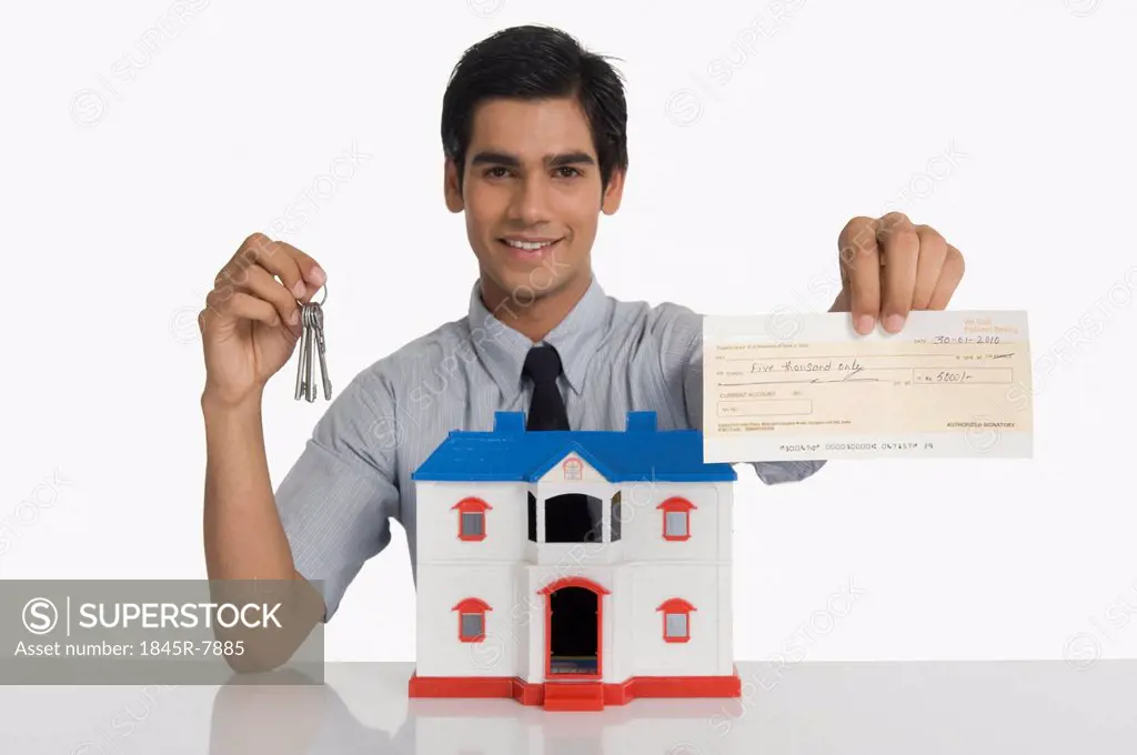 Real estate agent showing keys and a check near a model home