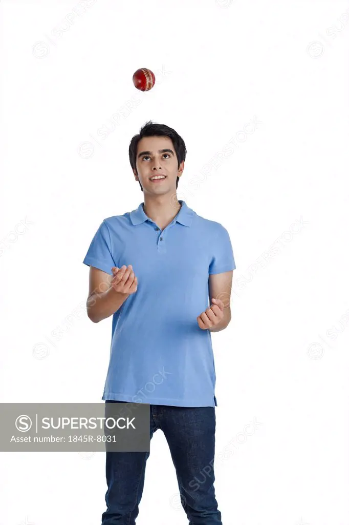 Man tossing a cricket ball and smiling