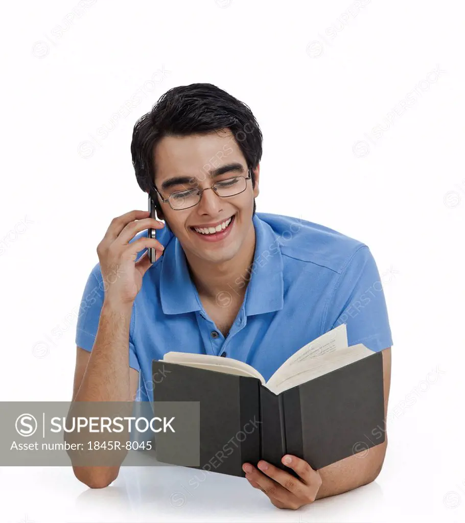 Happy man talking on a mobile phone while reading a book