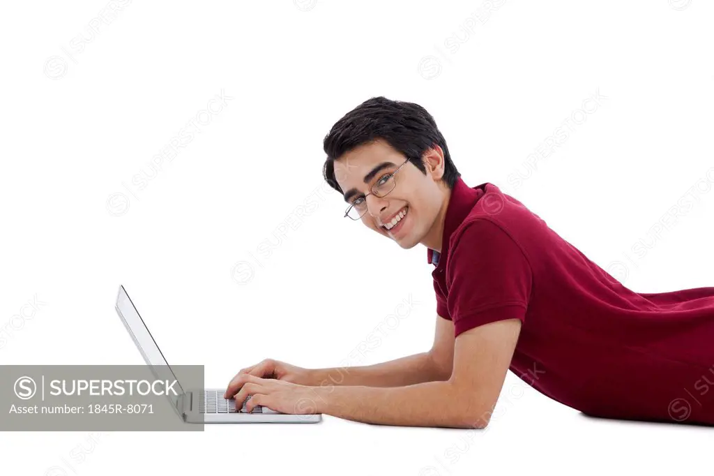 Happy man lying on the floor and using a laptop