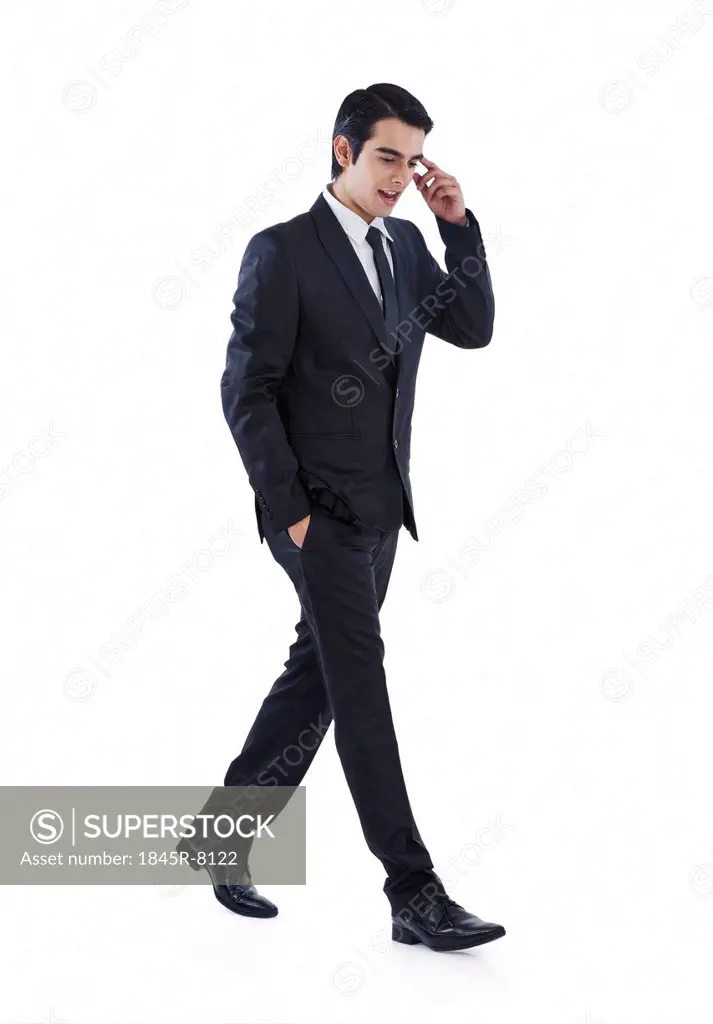 Businessman walking with his hands in pockets and thinking