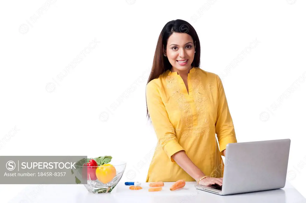 Woman using a laptop in a kitchen and smiling