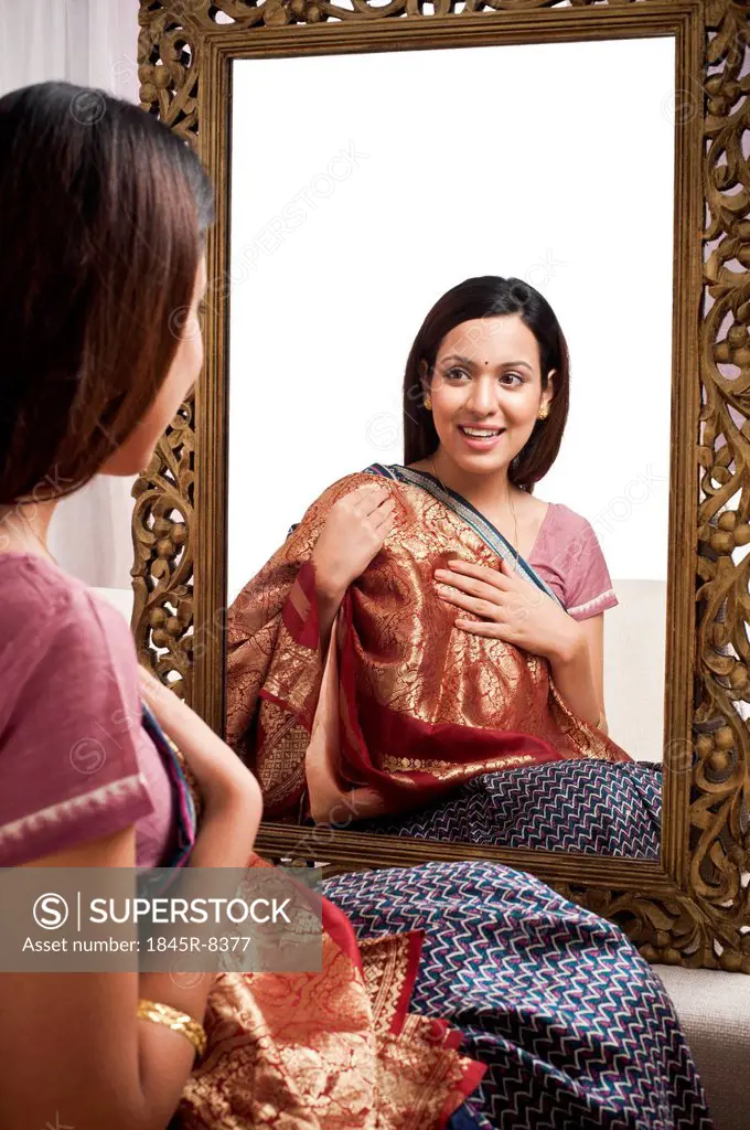 Reflection of a woman in mirror trying a sari on herself