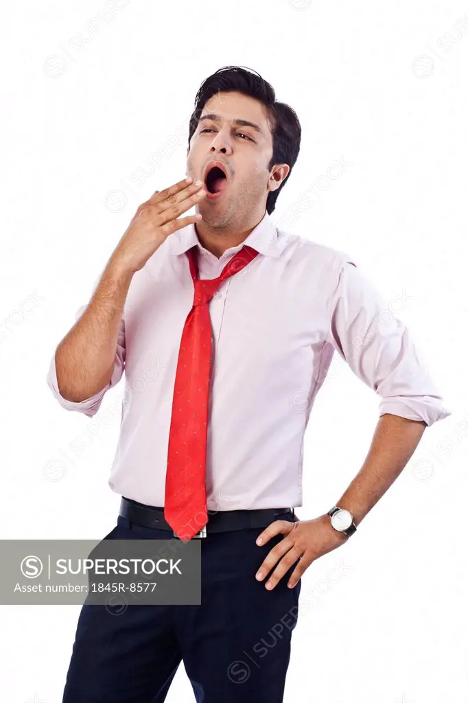 Businessman yawning with his hand on hip