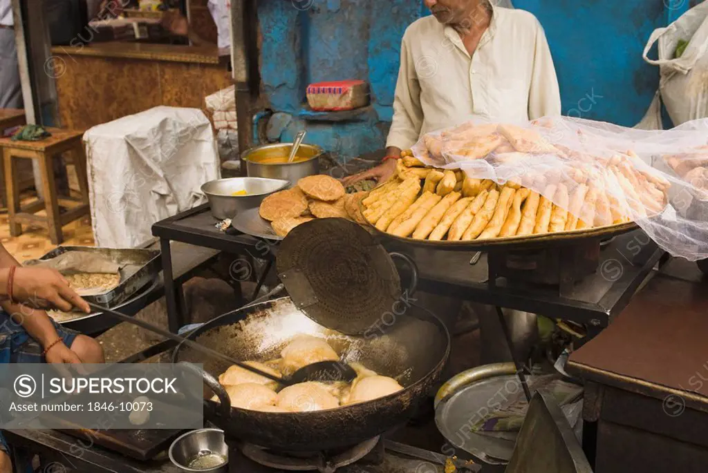 Man frying poori at a food stall, New Delhi, India