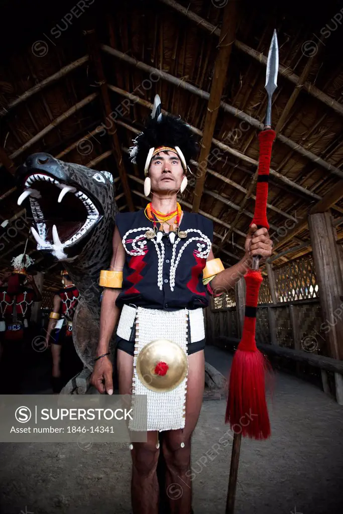 Naga tribal warrior in traditional outfit standing with a spear in a hut, Hornbill Festival, Kohima, Nagaland, India