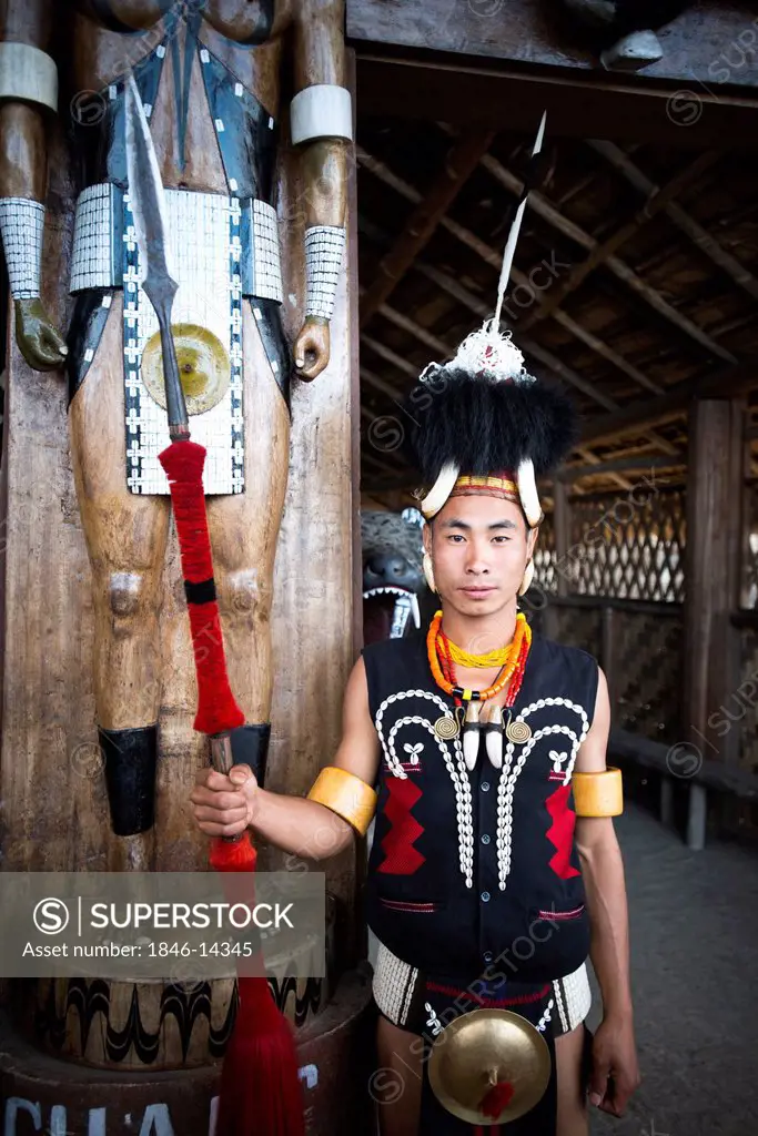 Naga tribal warrior in traditional outfit standing with a spear in a hut, Hornbill Festival, Kohima, Nagaland, India