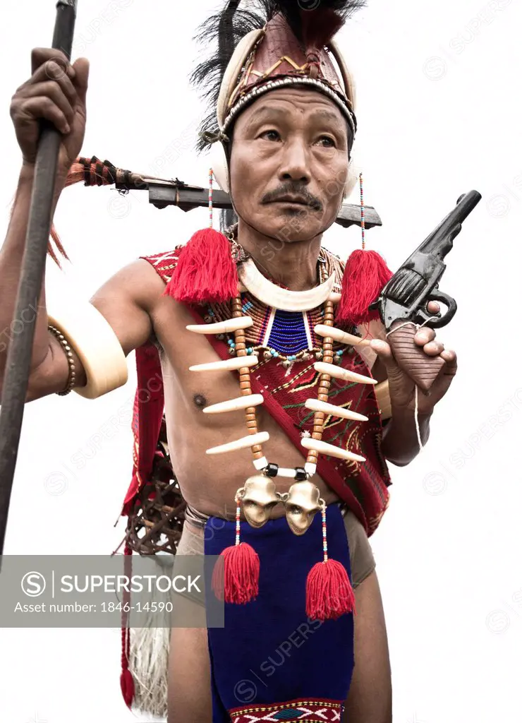 Naga tribal warrior in traditional outfit holding a spear and a handgun, Hornbill Festival, Kohima, Nagaland, India