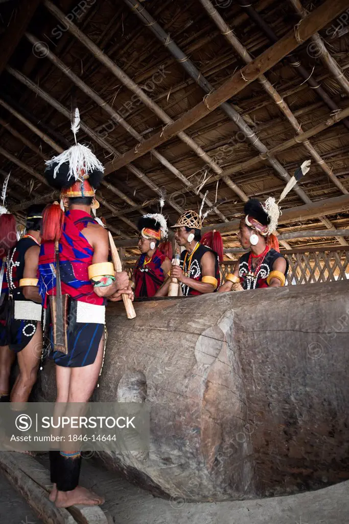 Naga tribal men in traditional outfit playing log drum, Hornbill Festival, Kohima, Nagaland, India
