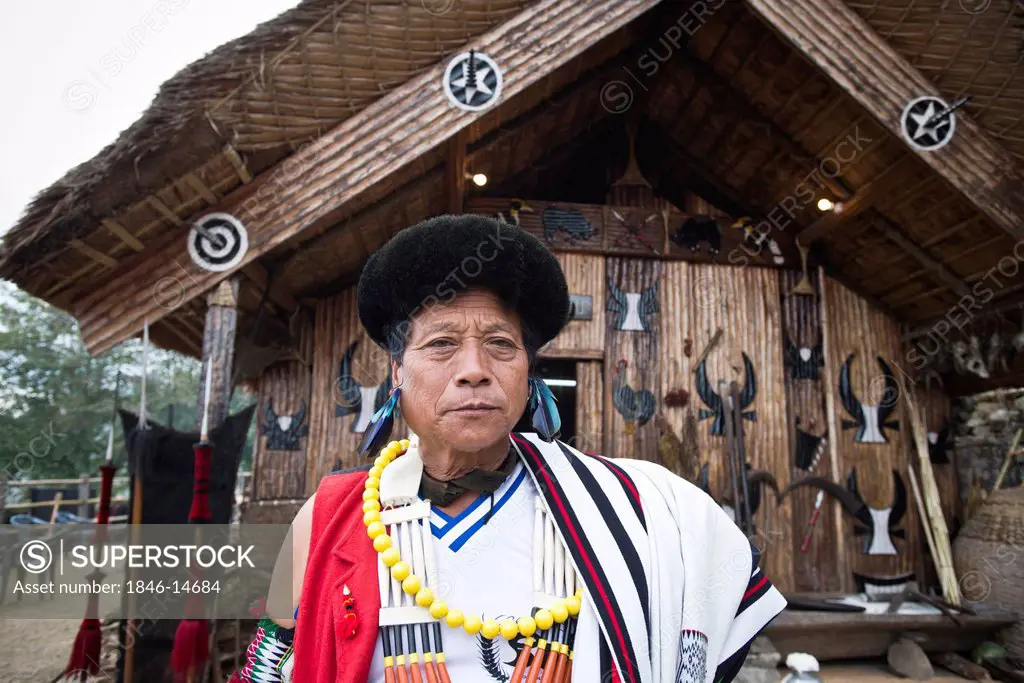 Naga tribal man standing outside a hut, Hornbill Festival, Kohima, Nagaland, India