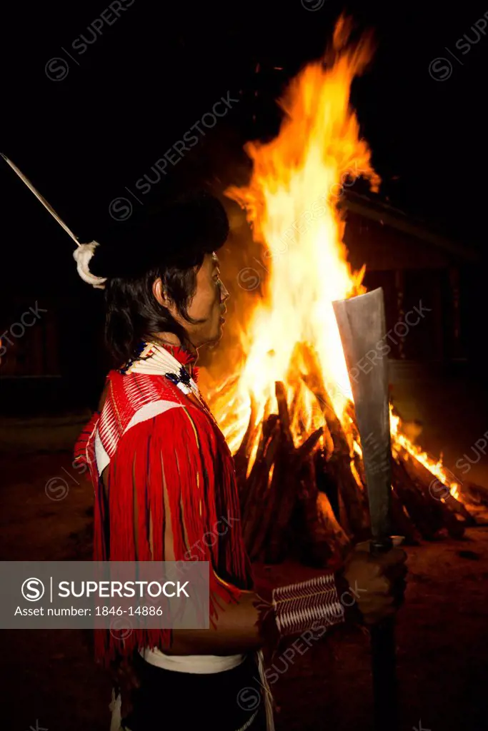 Naga tribesman holding a machete in front of fire during the annual Hornbill Festival at Kisama, Kohima, Nagaland, India