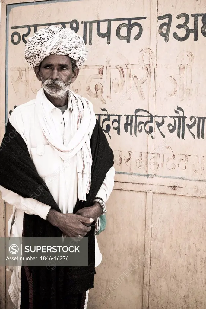 Senior man standing in front of a closed metal door, Pushkar, Ajmer, Rajasthan, India