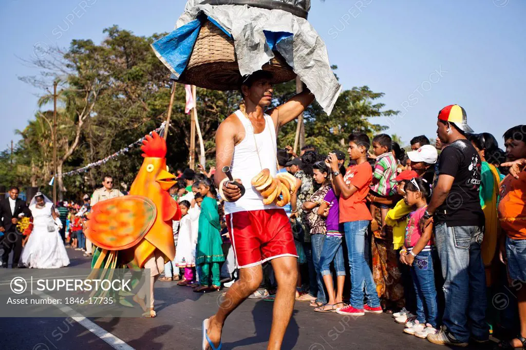 Man carrying basket on his head at traditional procession in a carnival, Goa Carnivals, Goa, India