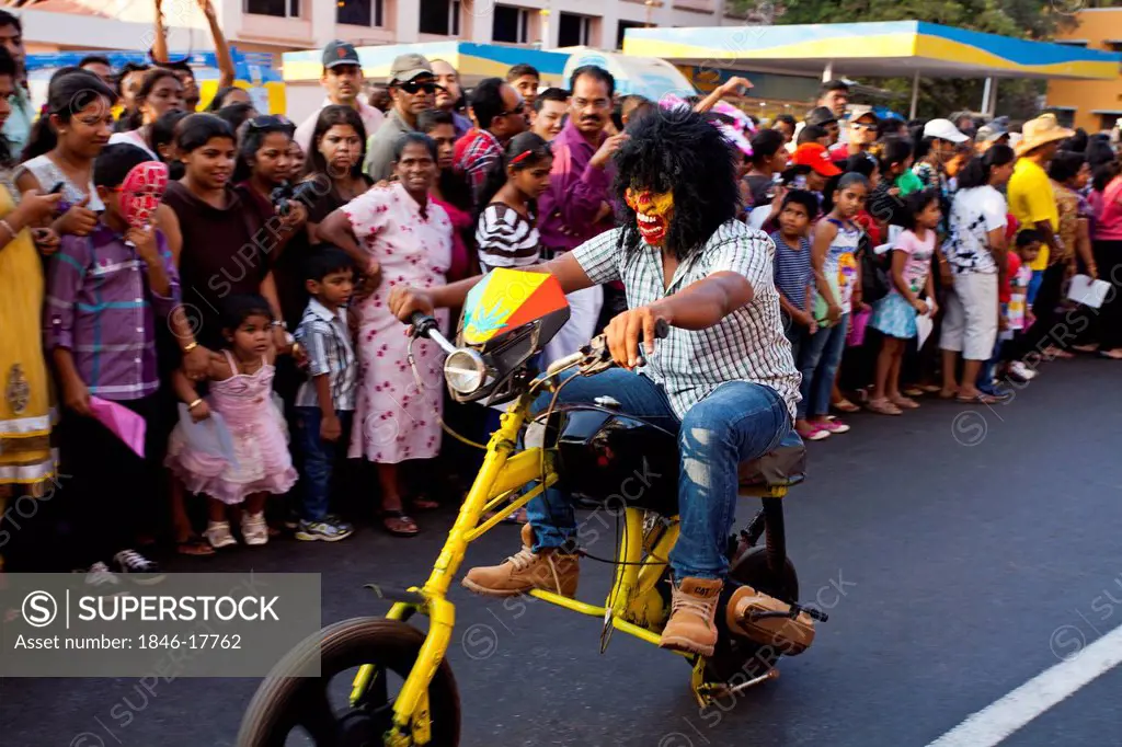 Man riding bike entertaining crowd in a carnival, Goa Carnivals, Goa, India