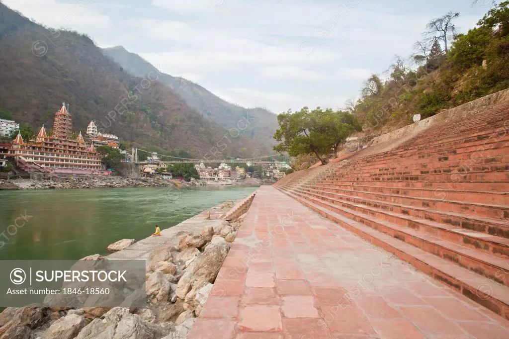 Steps on ghat at River Ganges with Lakshman Jhula and Trayambakeswar temple in the background, Lakshman Jhula, Rishikesh, Dehradun District, Uttarakha...