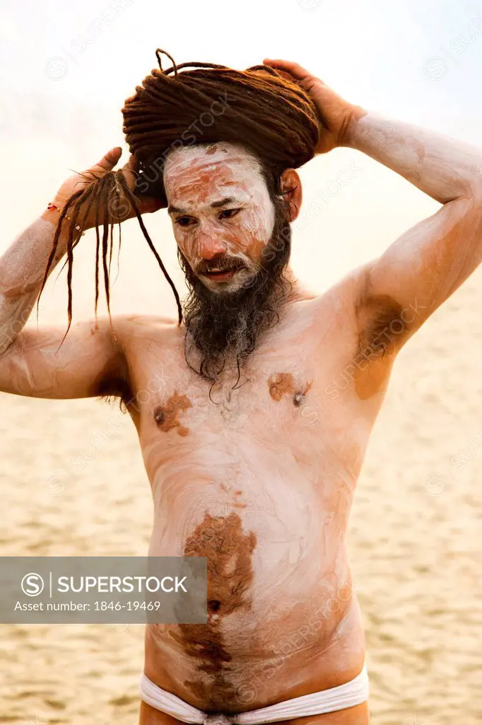 Naga Sadhu ties his hair during the first royal bath procession in Kumbh Mela festival, Allahabad, Uttar Pradesh, India