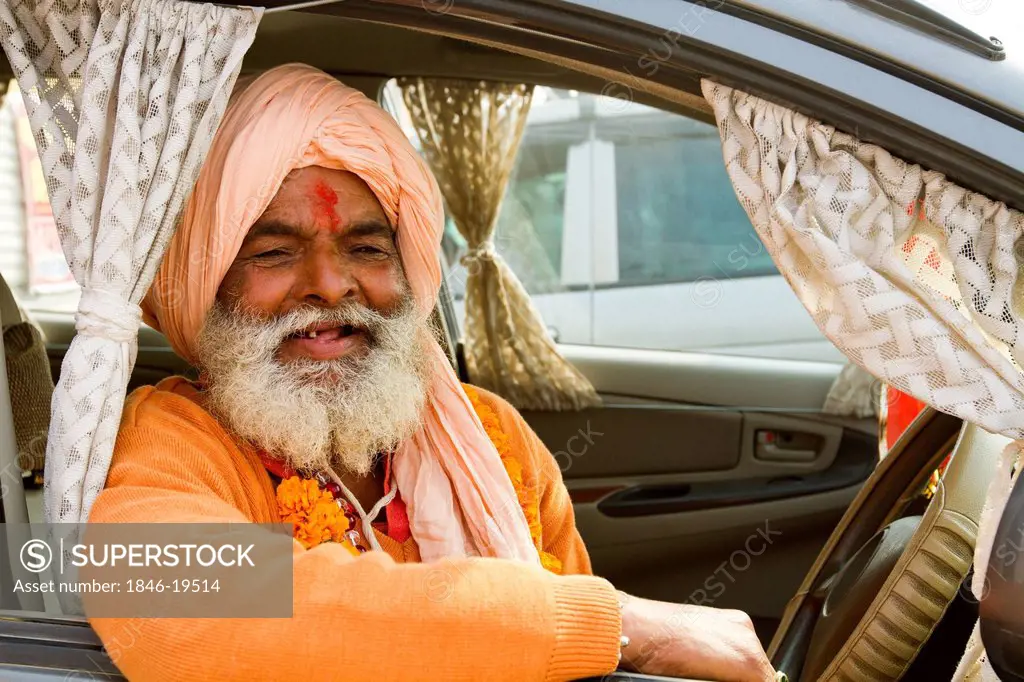 Sadhu sitting in a car and smiling during the first royal bath procession in Kumbh Mela festival, Allahabad, Uttar Pradesh, India