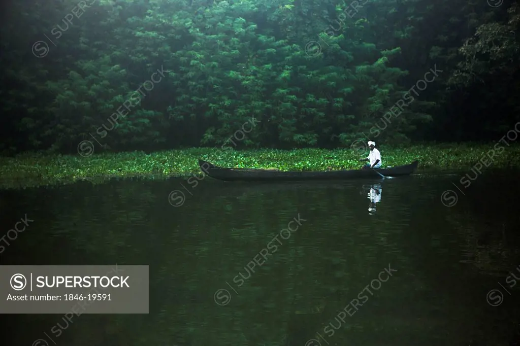 Man rowing a canoe in a lagoon, Kerala Backwaters, Alappuzha District, Kerala, India