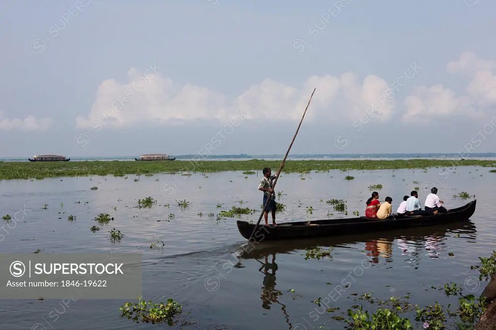 Tourists in a canoe with houseboats in the background, Kerala Backwaters, Alappuzha District, Kerala, India