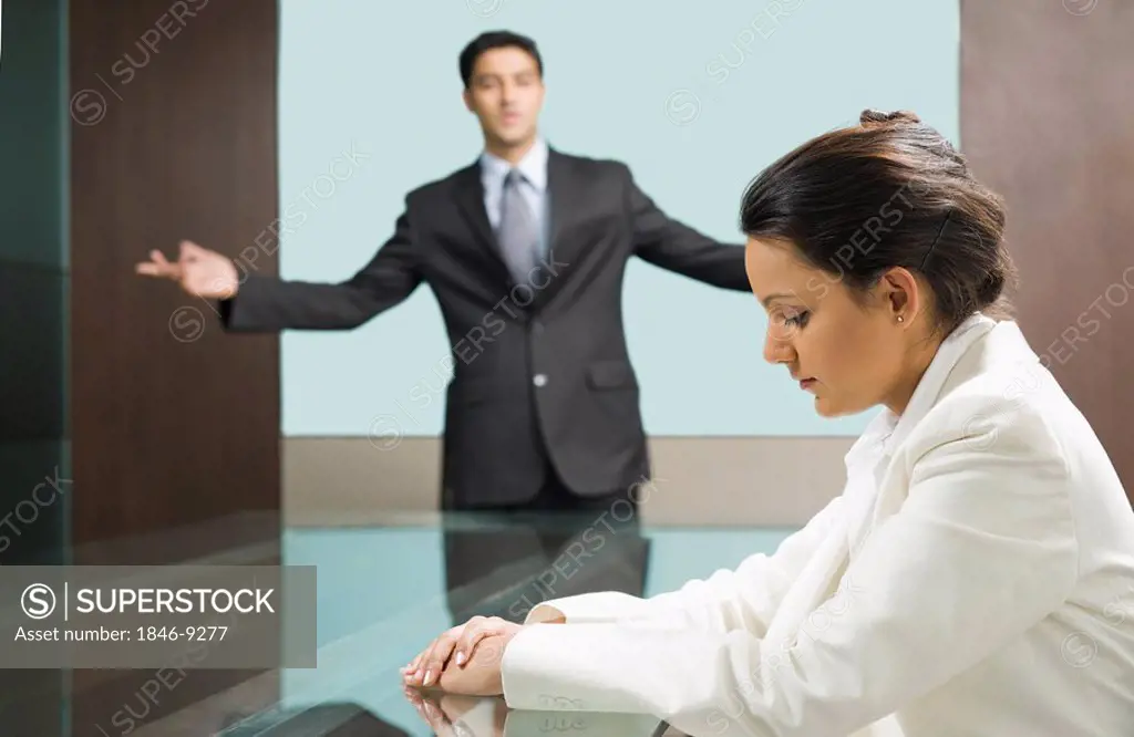 Businessman scolding a businesswoman in a board room