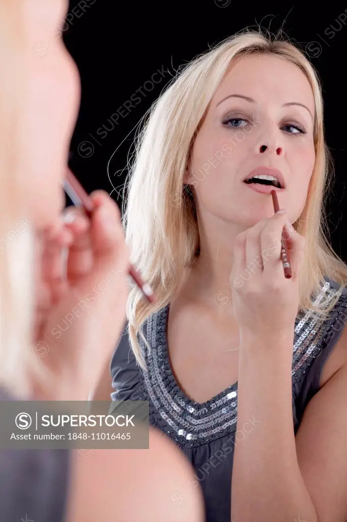 Young blonde woman, reflection, applying lip liner