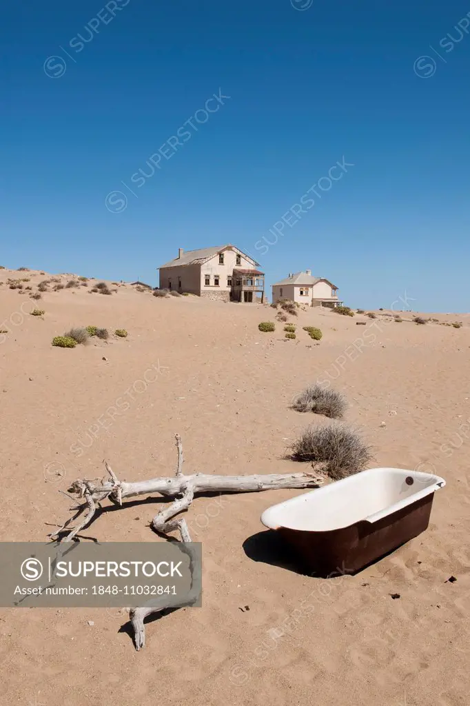 Old bathtub and houses of a former diamond miners settlement that is slowly covered by the sand of the Namib Desert, Kolmanskop, Karas, Namibia
