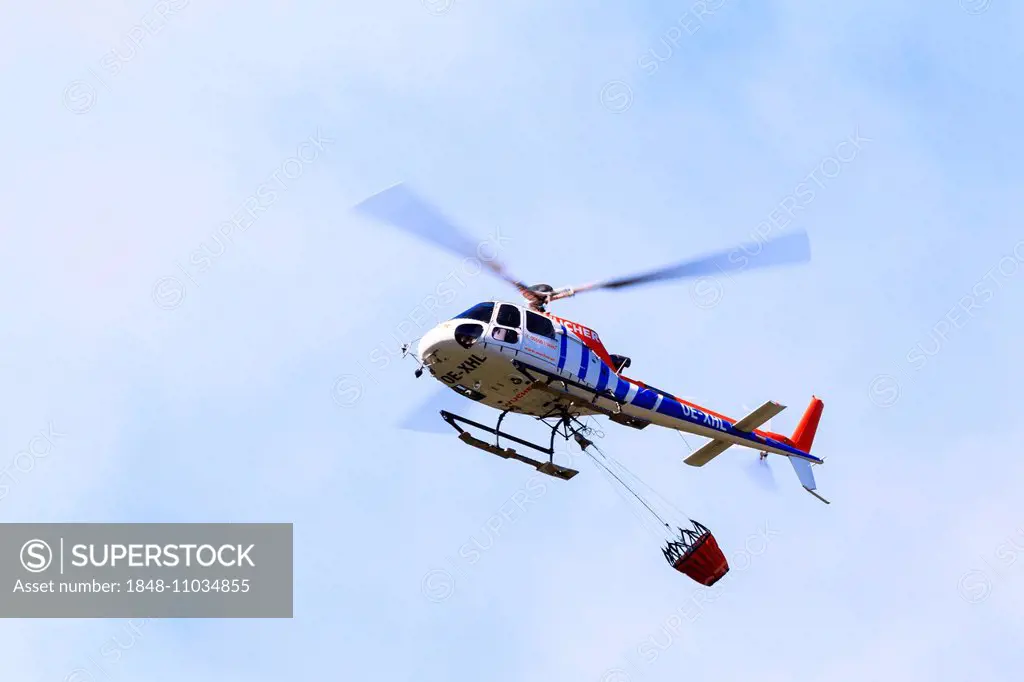 Helicopter with a water bucket during a forest fire, Tyrol, Austria