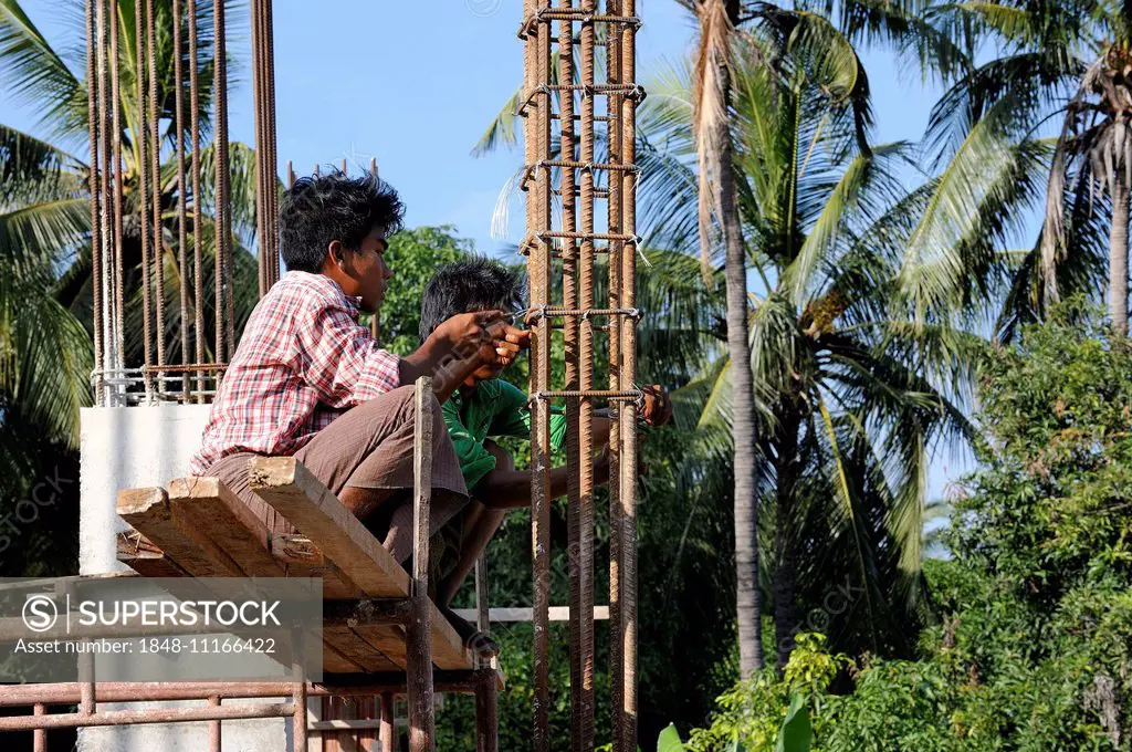 Construction workers on a high rise construction site wire rebar, Mandalay, Myanmar