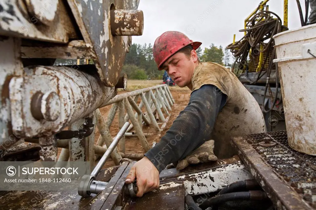 A worker takes apart a natural gas drilling rig in the Antrim Shale field of northern Michigan, Mancelona, Michigan, USA